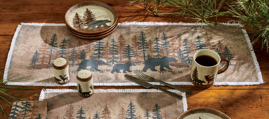Table setting with bear and forest design placemats and plates on a wooden table.