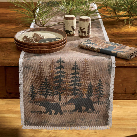 Table setting with a nature-themed table runner, plates, and napkins on a wooden table.