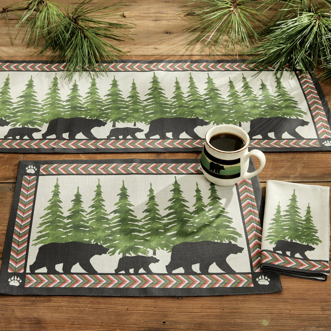 Set of placemats with bear and forest design on a wooden table.