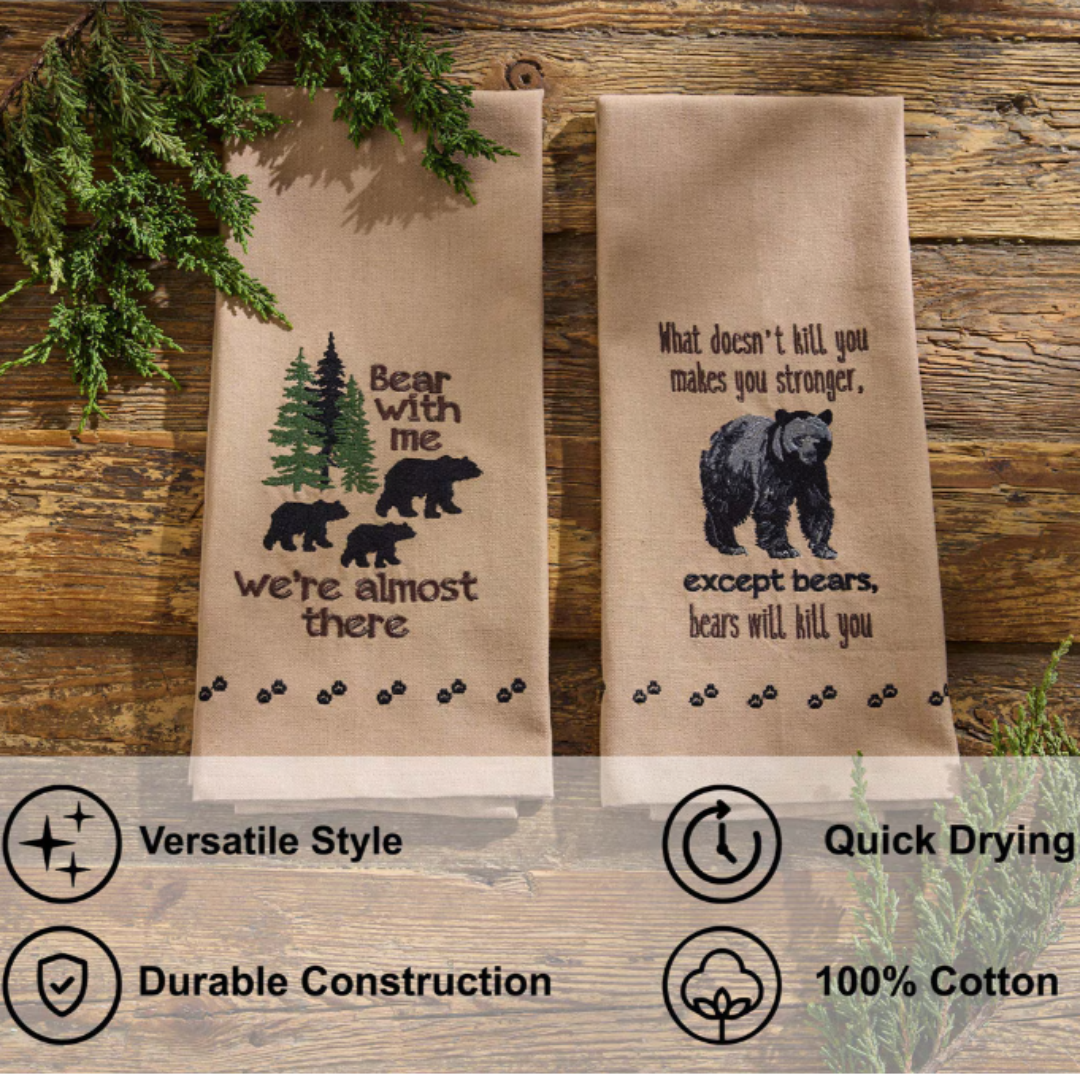 Two embroidered tea towels with bear designs on a wooden background
