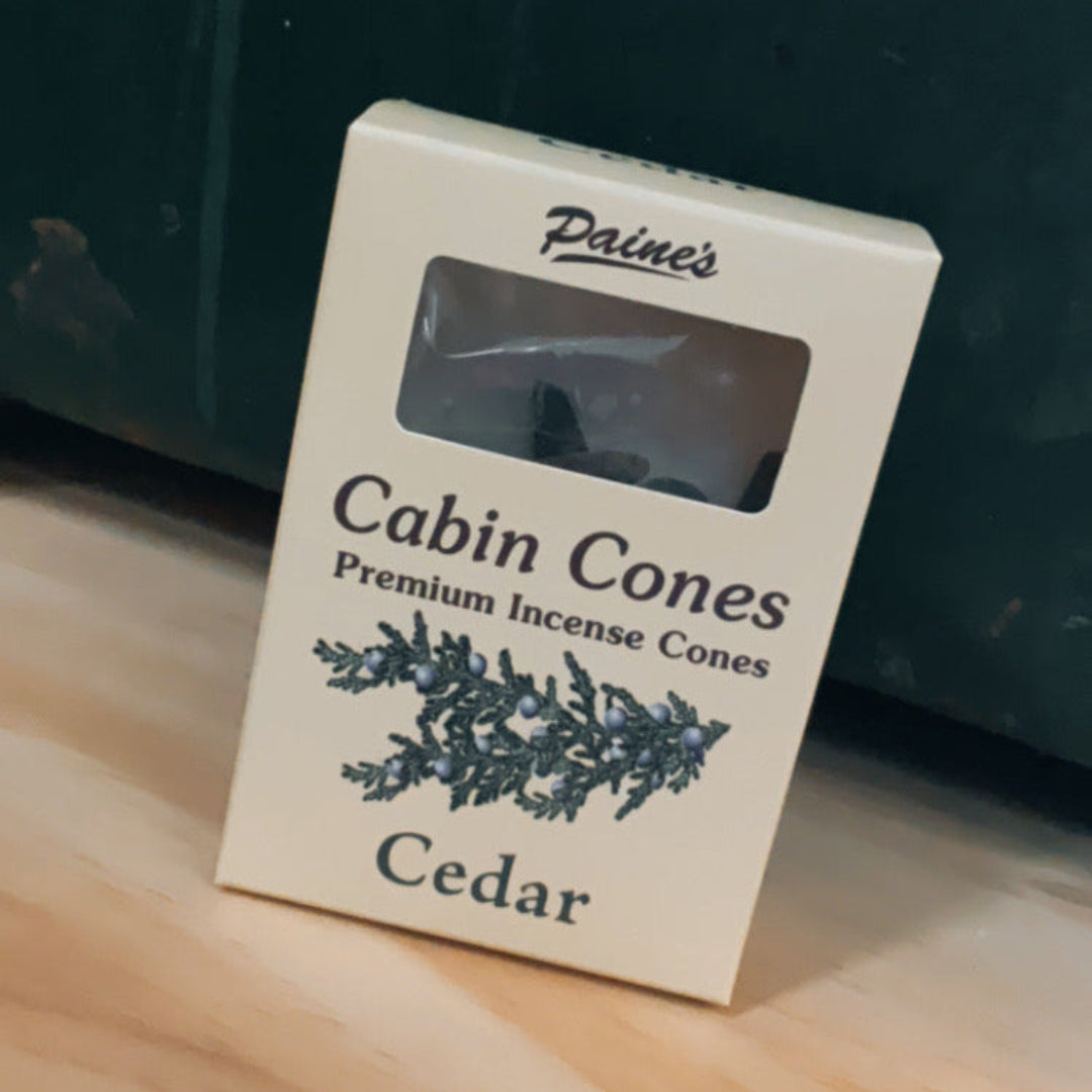 Box of Paine's Cabin Cones Cedar incense cones on a wooden surface with a dark background.