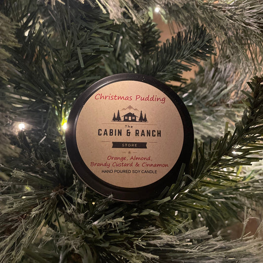 Candle labeled 'Christmas Pudding' from 'The Cabin & Ranch Store' on a Christmas tree.