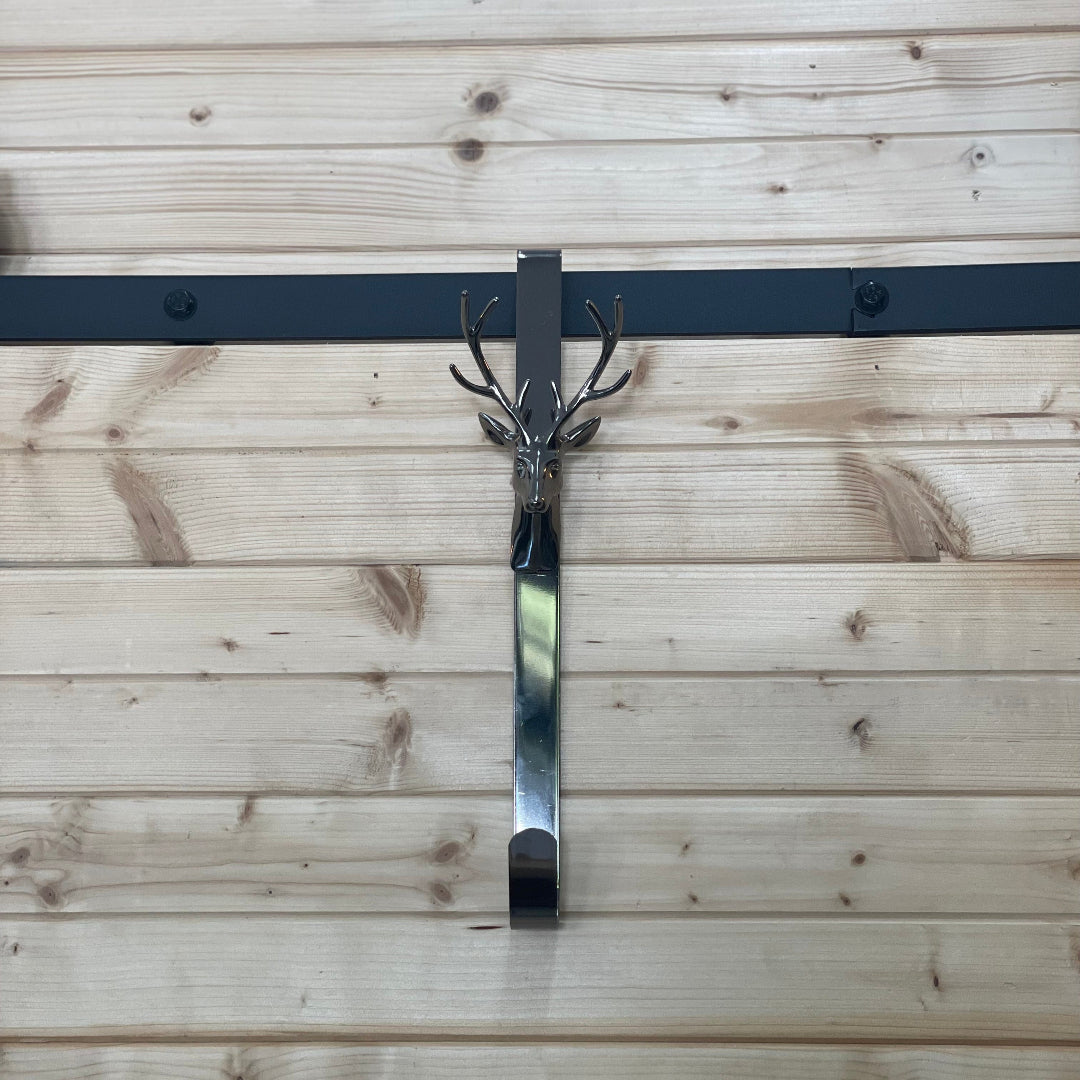 Decorative metal wall hook with deer head design on a wooden background