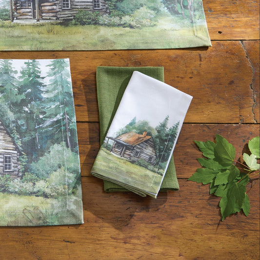 Table setting with placemats, napkins, and cutlery featuring a cabin in the woods design on a wooden table.