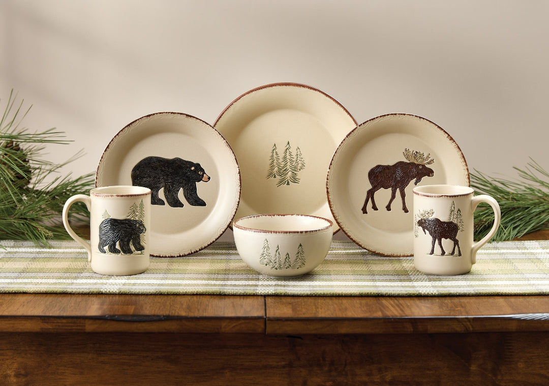 Lodge Ceramic tableware set with Moose & Bear illustrations on a wooden surface with greenery.