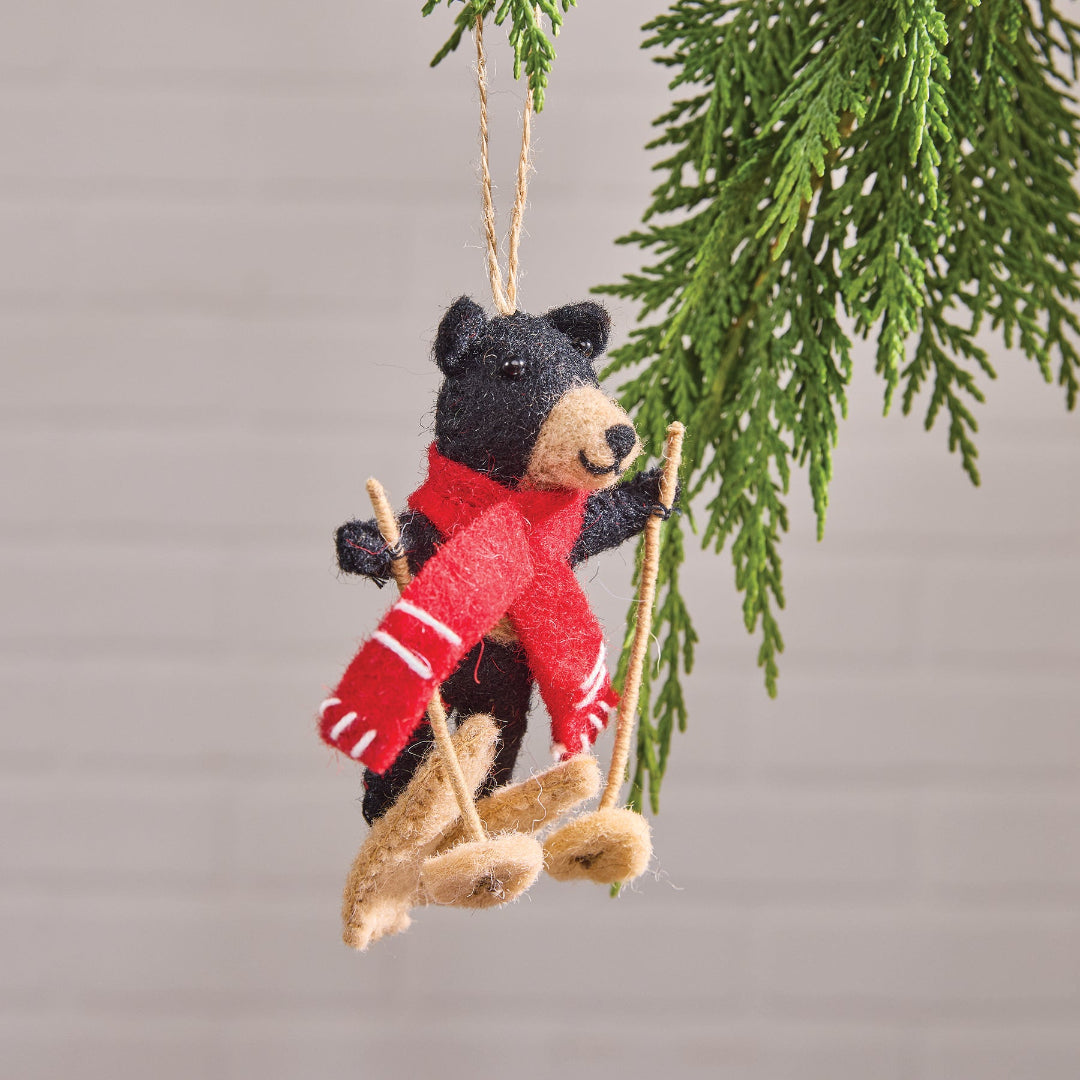 Bear Felt ornament with a red scarf and skis hanging from a branch.