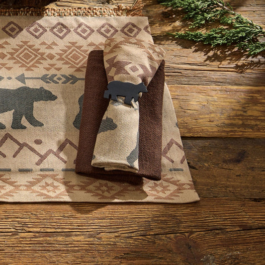 Table setting with bear-themed placemats, plates, and cutlery on a wooden table.