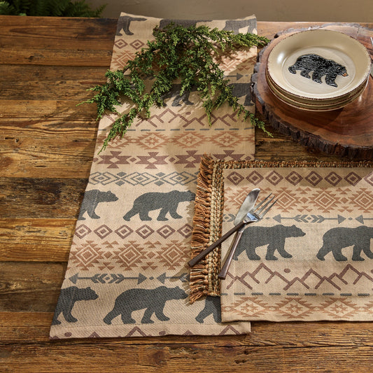 Table setting with bear-themed placemats, plates, and cutlery on a wooden table.