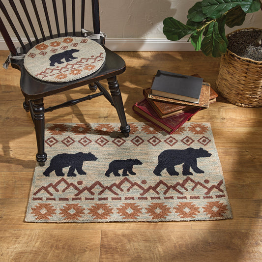 Decorative rug with bear design on a wooden floor, chair with patterned cushion, and books.