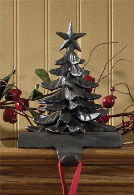 Decorative iron Christmas tree Stocking Holder with a star on top, hanging on a wooden surface.