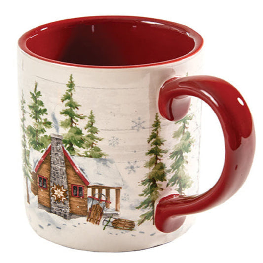 Ceramic mug with a winter scene featuring a cabin and trees on a white background.
