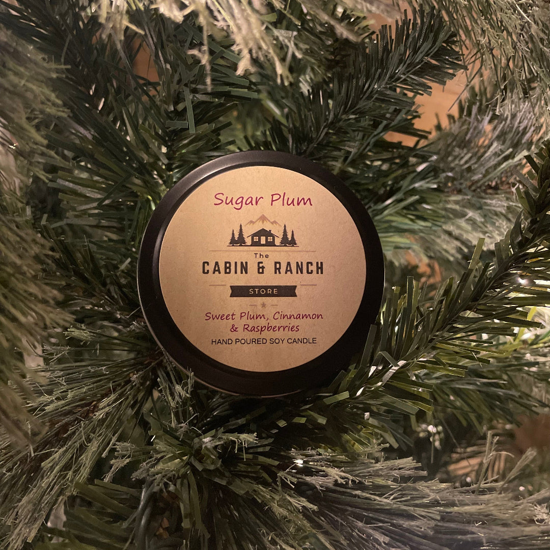 Candle labeled 'Sugar Plum' from 'The Cabin & Ranch' brand on a Christmas tree.