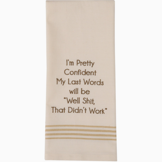 Beige towel with brown humorous text and decorative lines on a white background