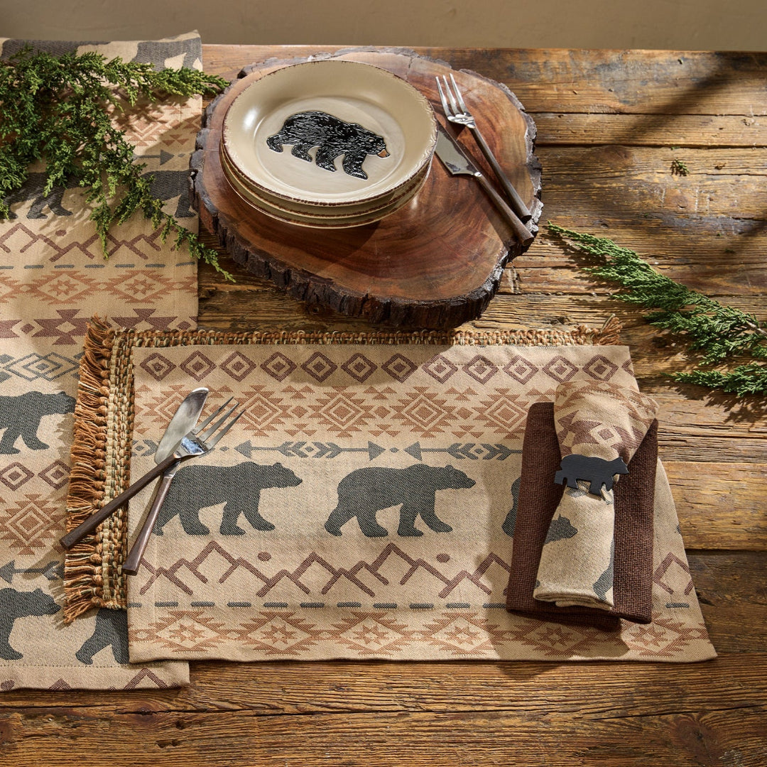 Table setting with bear-themed placemats, plates, and cutlery on a wooden table.