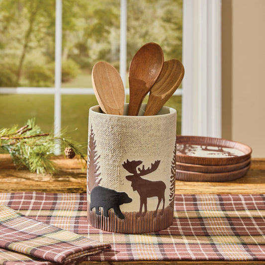 Wilderness themed utensils crook with moose and bear designs on a table with plaid table runner.